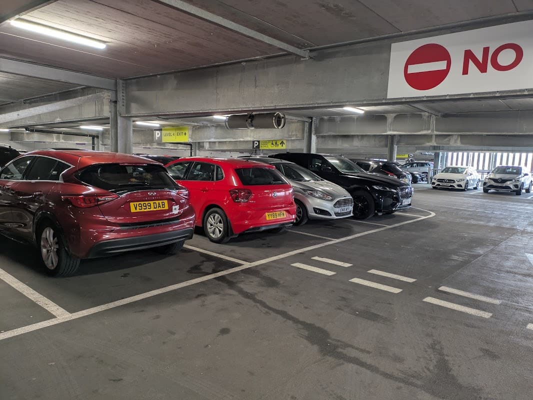 Multi-storey car park with parked vehicles, including red, silver, and black cars, and a "No Entry" sign visible.