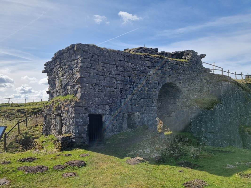Historic stone structure of Toft Gate Lime Kiln with grassy surroundings and blue sky in Bewerley, Yorkshire.
