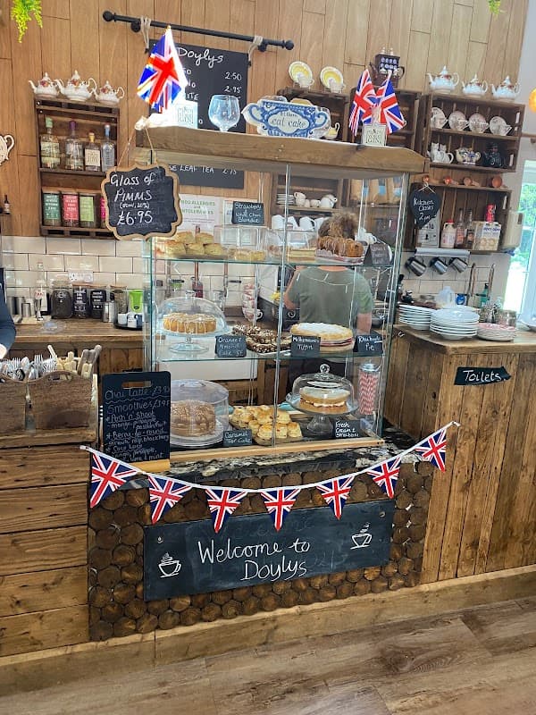 Display case filled with baked goods, Union Jack bunting, and a wooden counter in a cozy tearoom setting.
