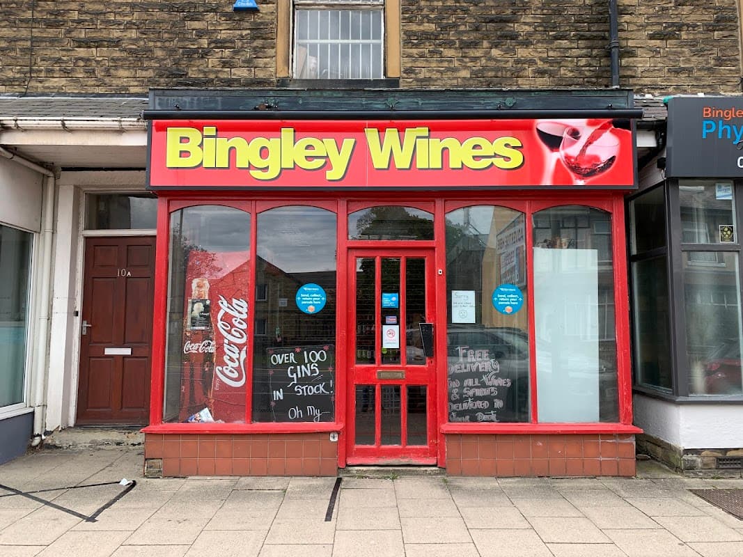 Bright red storefront with "Bingley Wines" sign, large windows, and promotional signs for gin and Coca-Cola.