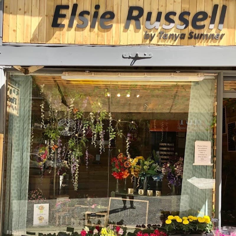 Floral shop window display featuring vibrant flowers, hanging greenery, and a welcoming sign in Bradford, Yorkshire.