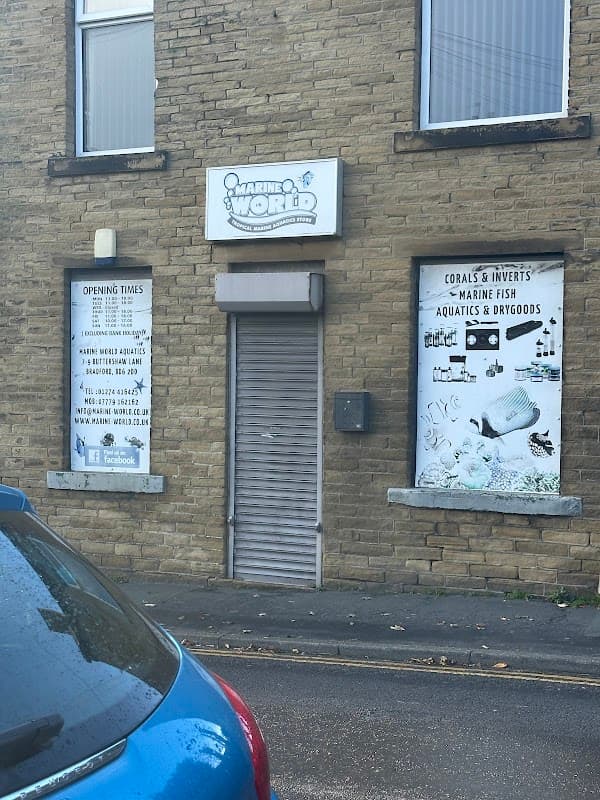 Sign for Marine World Aquatics on a stone building with posters for marine fish and dry goods.