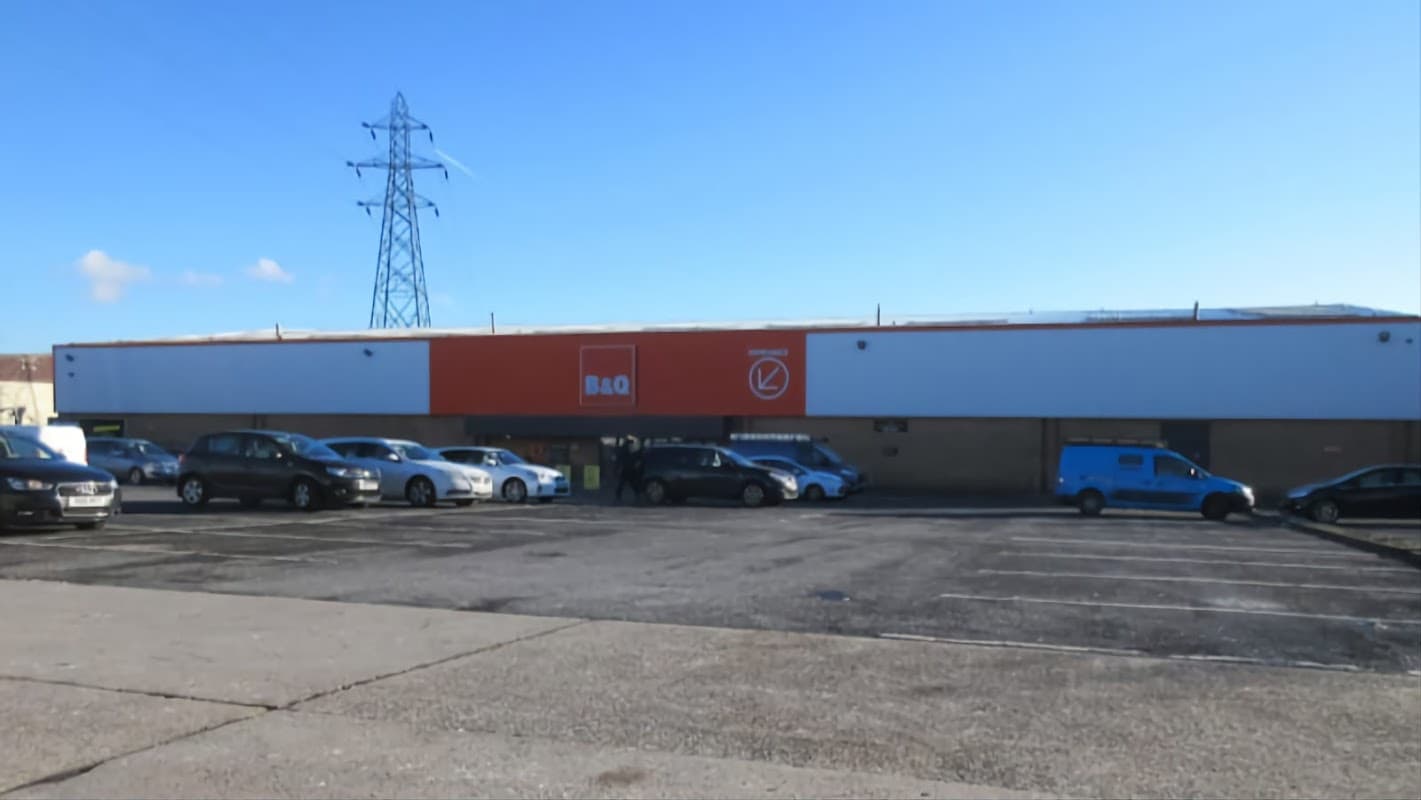 Homeware store with a large orange sign, parked cars, and a clear blue sky in Bradford, Yorkshire.
