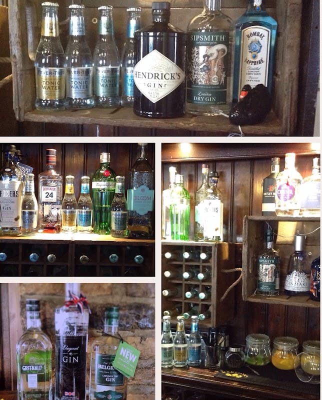 A rustic bar display featuring various gin bottles, mixers, and glassware against a wooden backdrop.