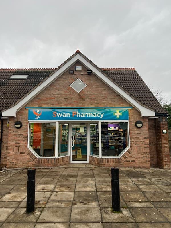 Swan Pharmacy storefront with a blue sign, large windows, and a brick facade in Brayton, North Yorkshire.