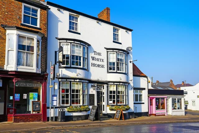 The White Horse guest house features a white exterior, large windows, and a welcoming entrance in a quaint Yorkshire street.