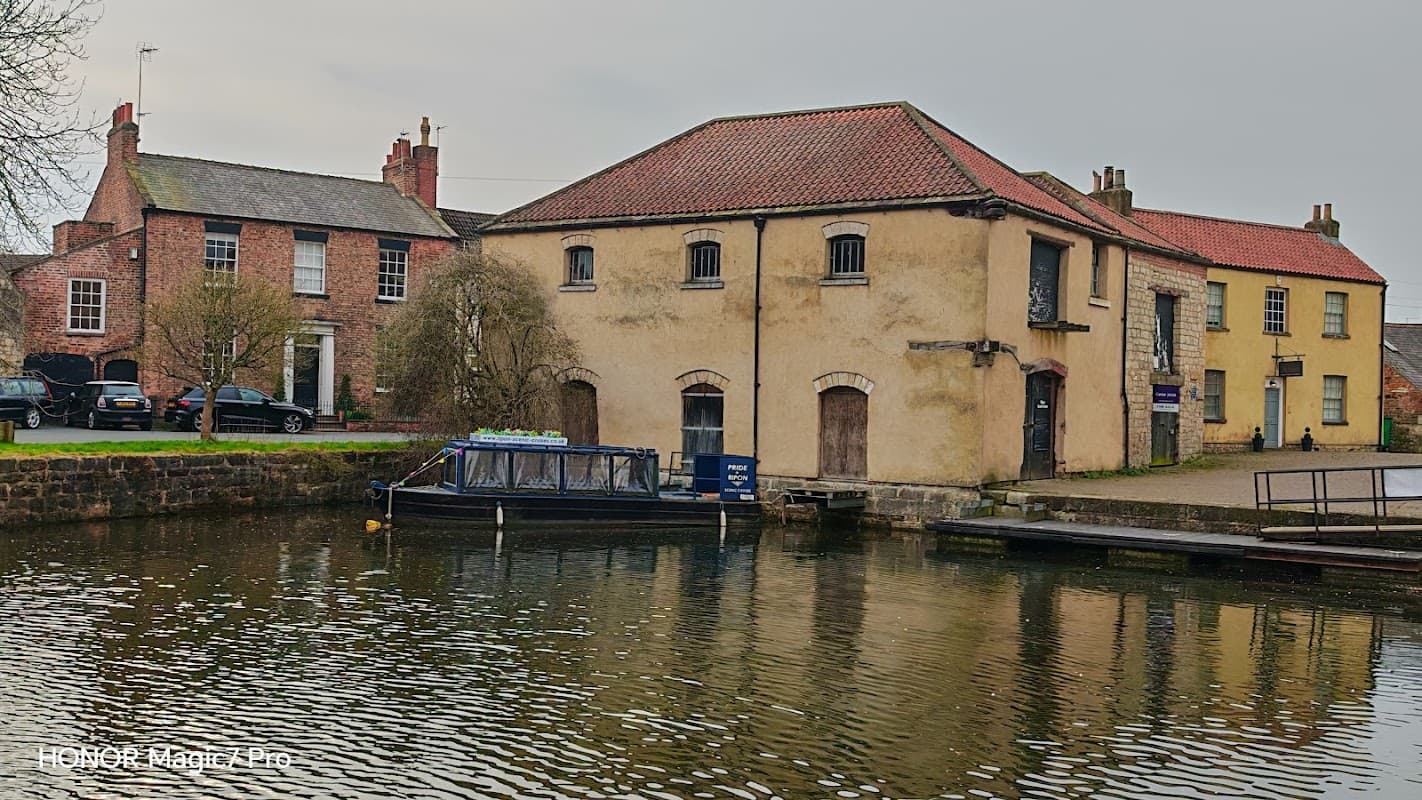 Ripon Canal Basin features a tranquil waterway, historic buildings, and a moored boat reflecting on the water.