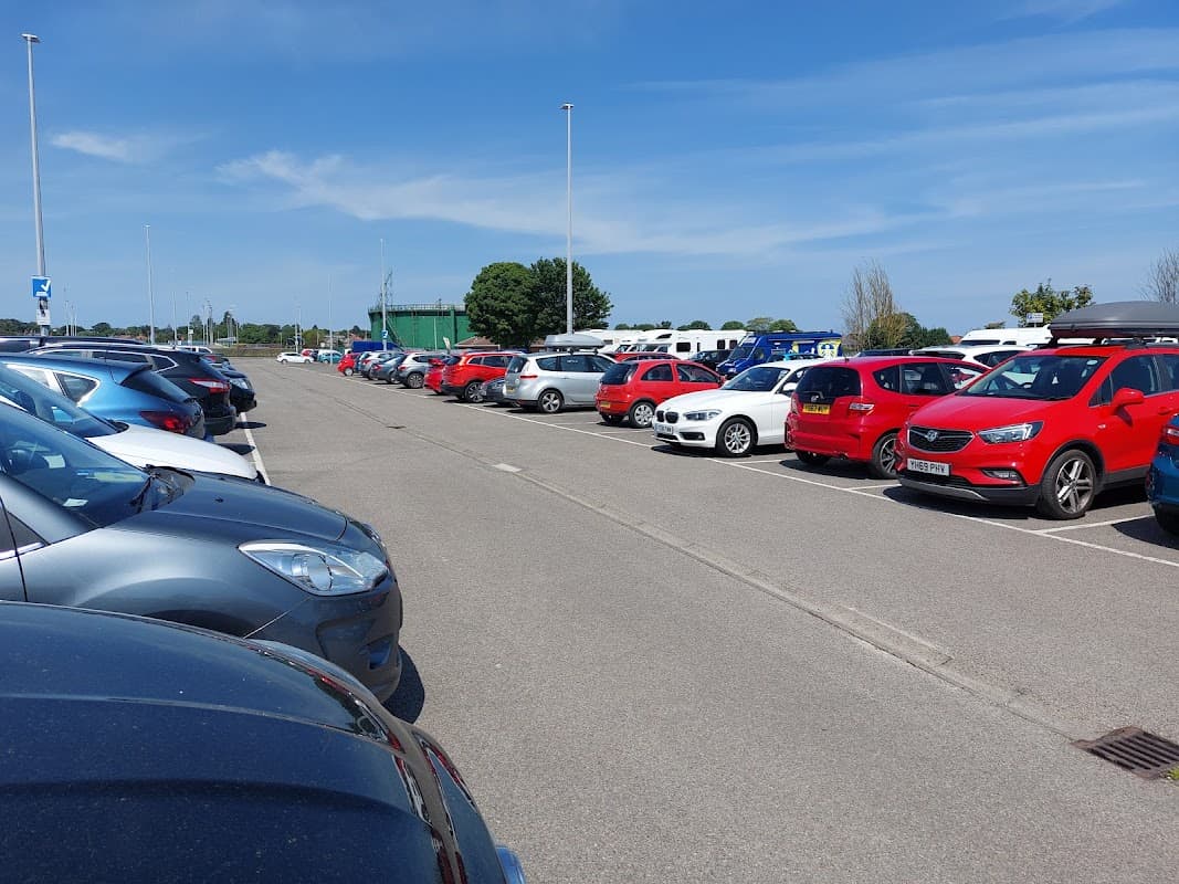 Pay & Display parking lot on Moorfield Road, featuring rows of parked cars in various colors under a clear blue sky.