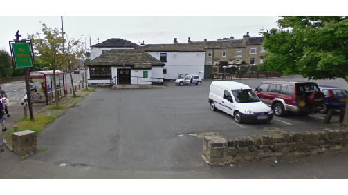 Pay & Display parking area in Brighouse, Yorkshire, with vehicles parked and a building in the background.