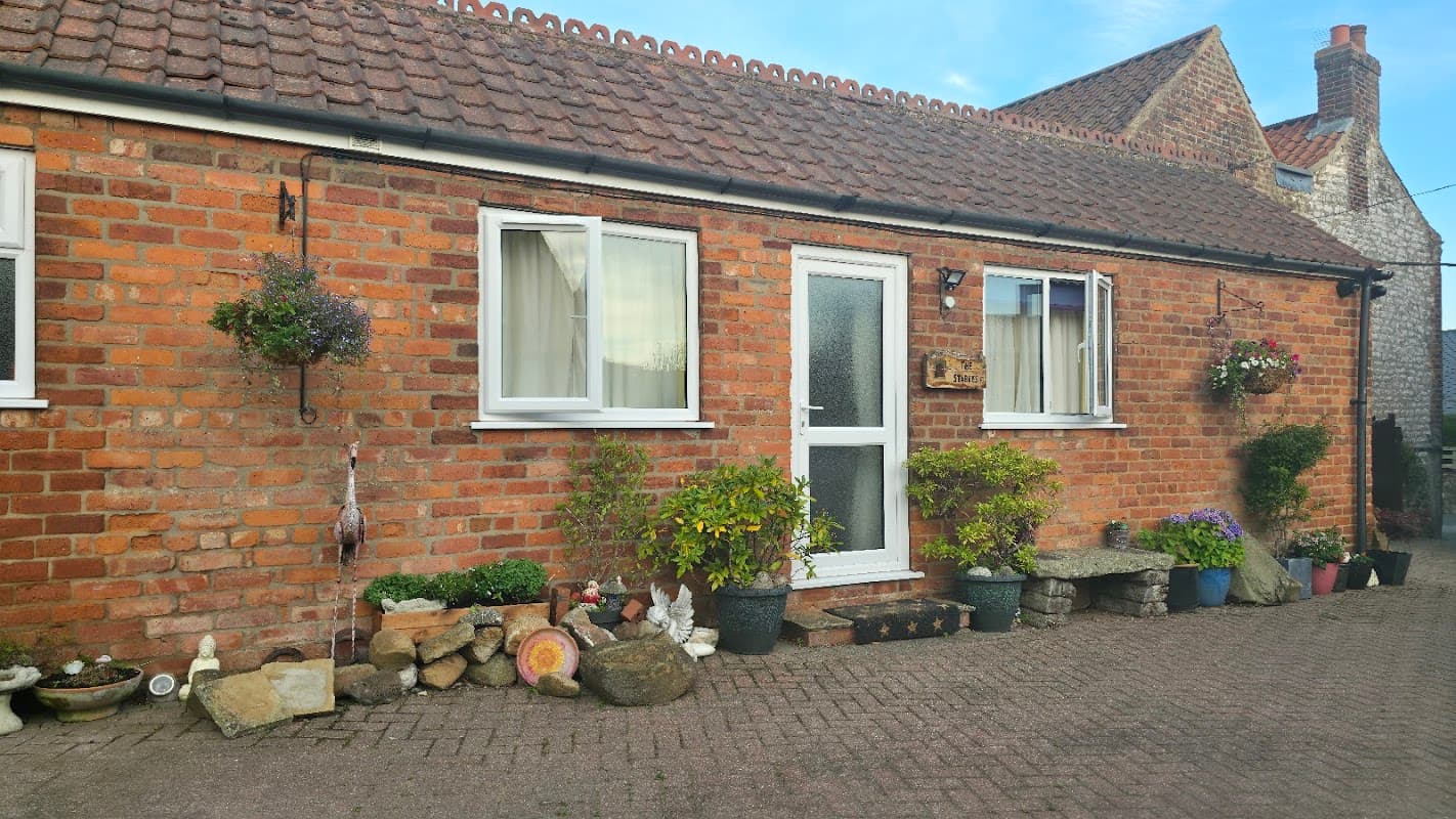Charming brick exterior of Stables Bed and Breakfast with flower pots, a welcoming door, and decorative stones.
