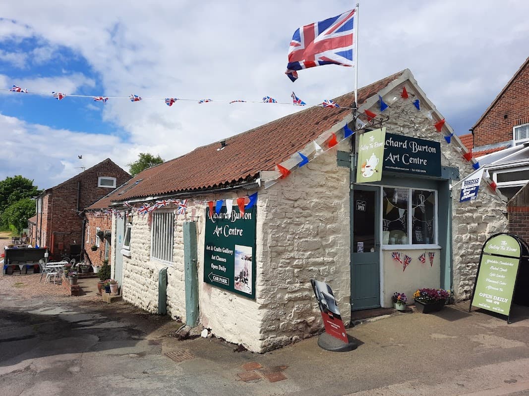 Quaint stone building with Union Jack flag, bunting, and art displays, located in Buckton and Bempton, Yorkshire.