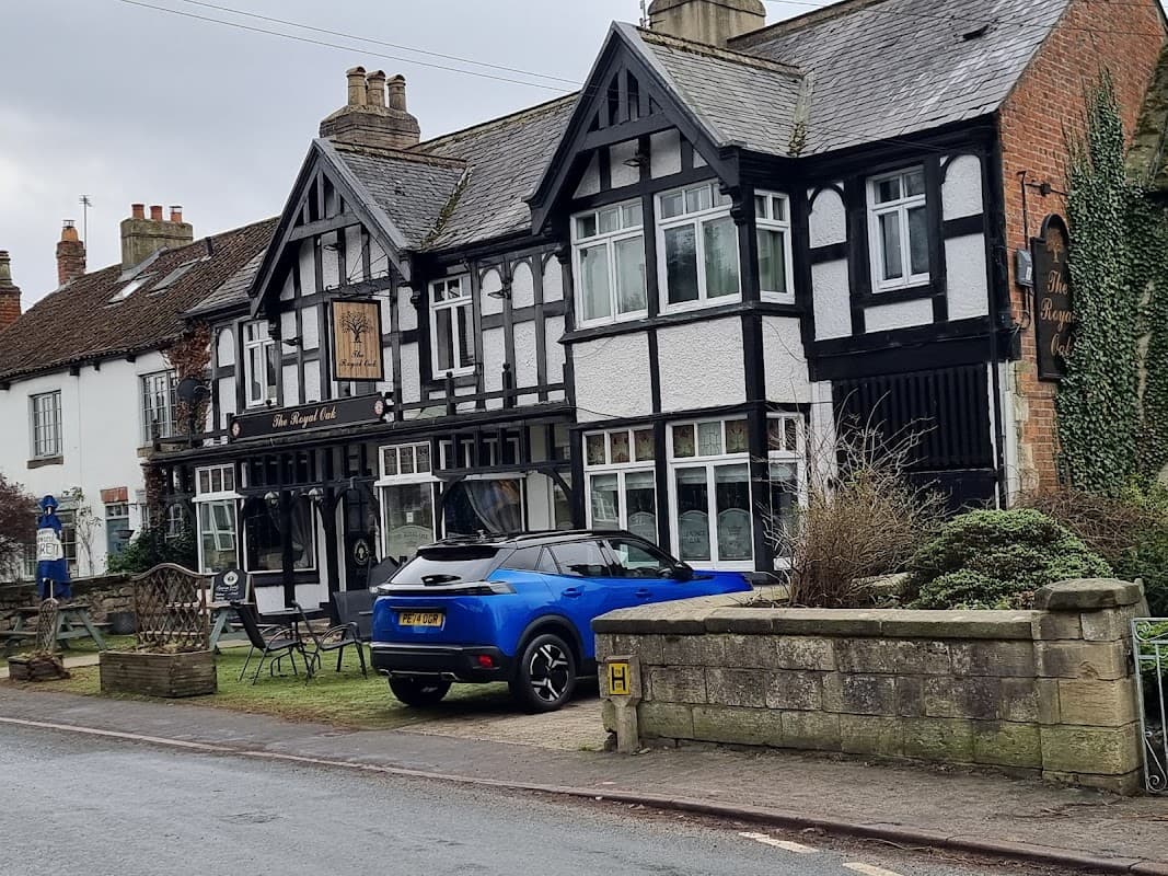 Tudor-style building with black and white facade, parked blue car, and outdoor seating in front.