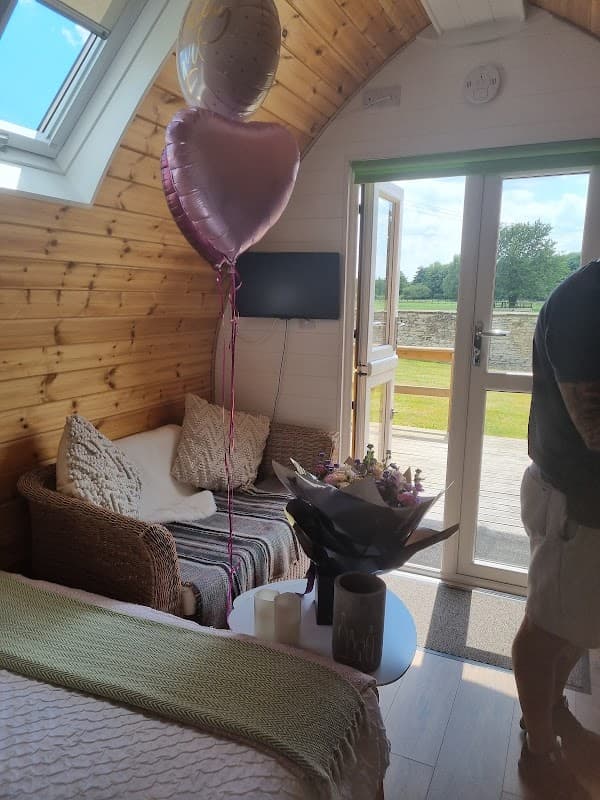 Cozy interior of a cabin featuring a balloon, flowers, and a view of the outdoors through large glass doors.
