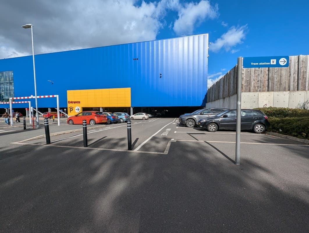 Ikea Sheffield Park and Ride with blue building, yellow entrance, parked cars, and sign for tram station.