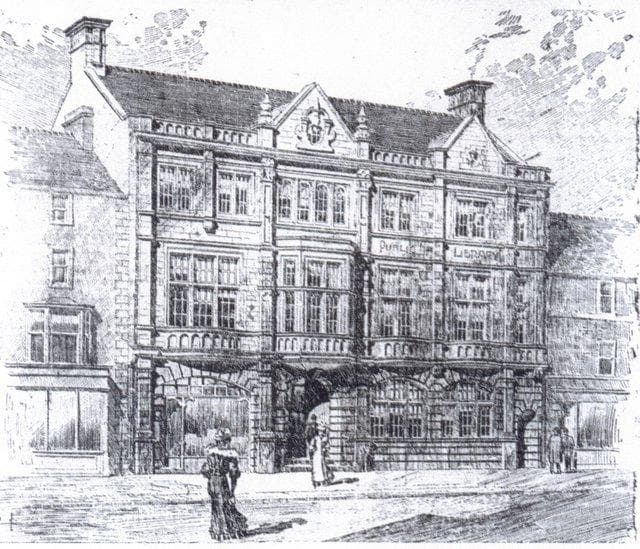 Historic building with intricate architectural details, featuring large windows and a prominent entrance, set in a town square.