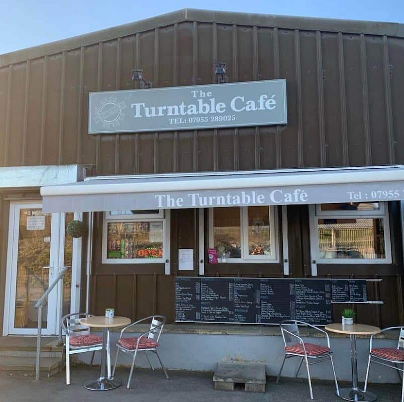 The Turntable Café features a rustic exterior, outdoor seating, and a menu board displayed prominently.