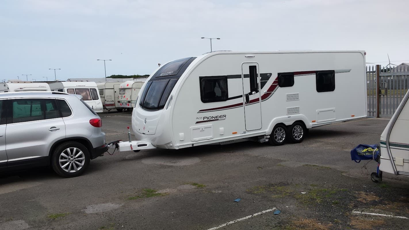 Caravan being towed by an SUV in a storage area with multiple caravans in the background.