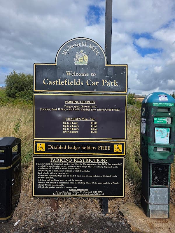 Welcome sign for Castlefields Car Park with parking charges, restrictions, and a nearby parking meter.