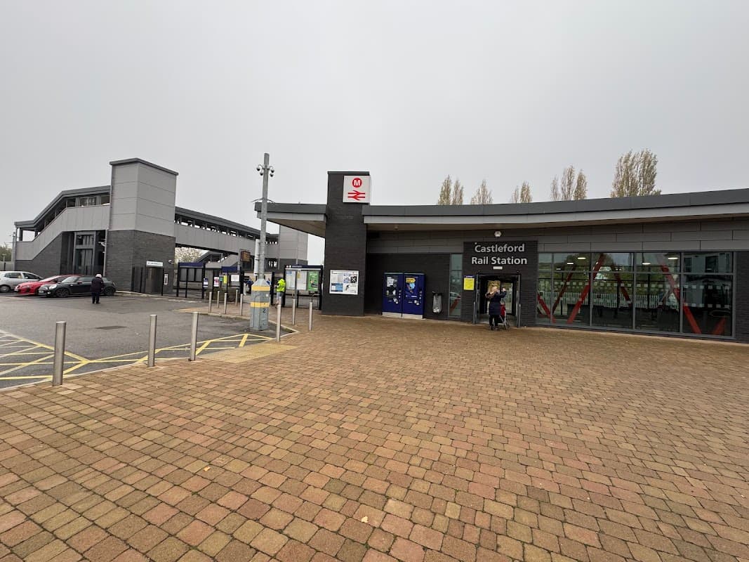 Castleford Rail Station entrance with modern architecture, surrounded by a paved area and bus stops nearby.