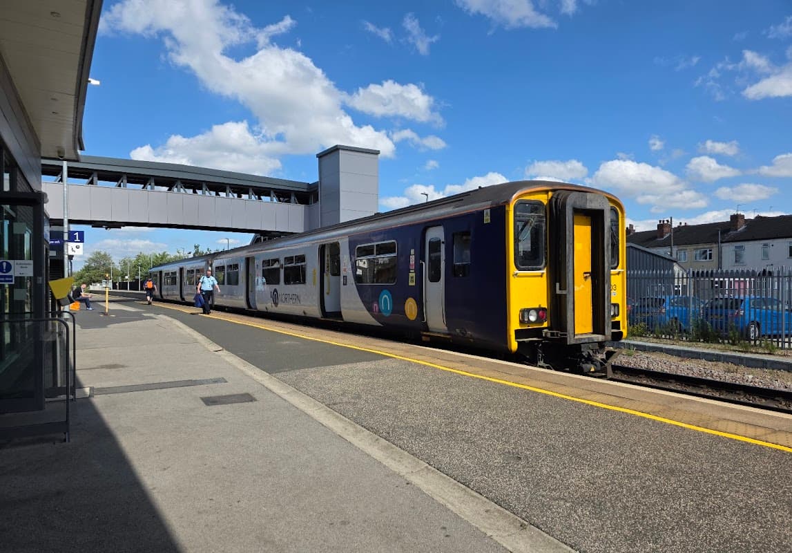 Train at a platform in Castleford, Yorkshire, with a blue sky and clouds overhead, and a pedestrian bridge in the background.