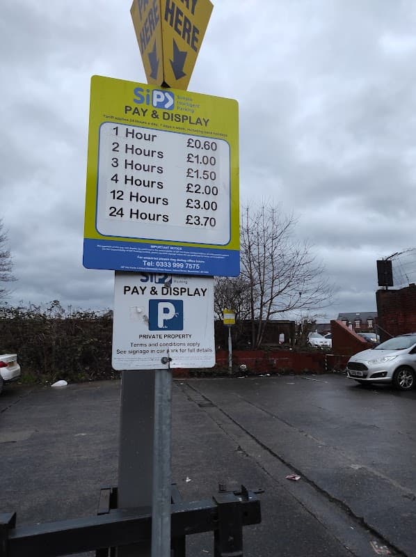 Parking sign detailing rates for various durations at Sagar parking in Castleford, with a car parked nearby.