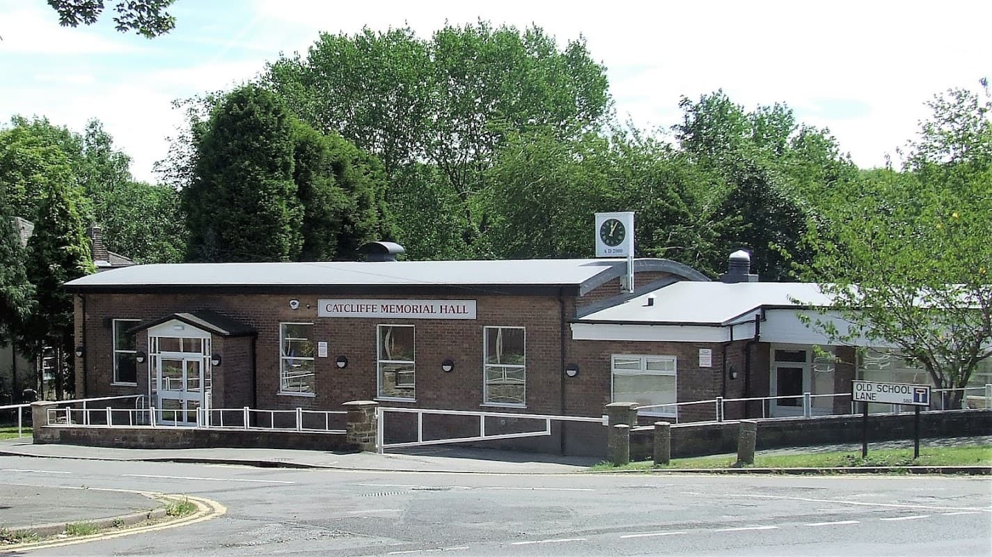 Catcliffe Memorial Hall, a modern brick building with large windows, surrounded by trees and a clear blue sky.