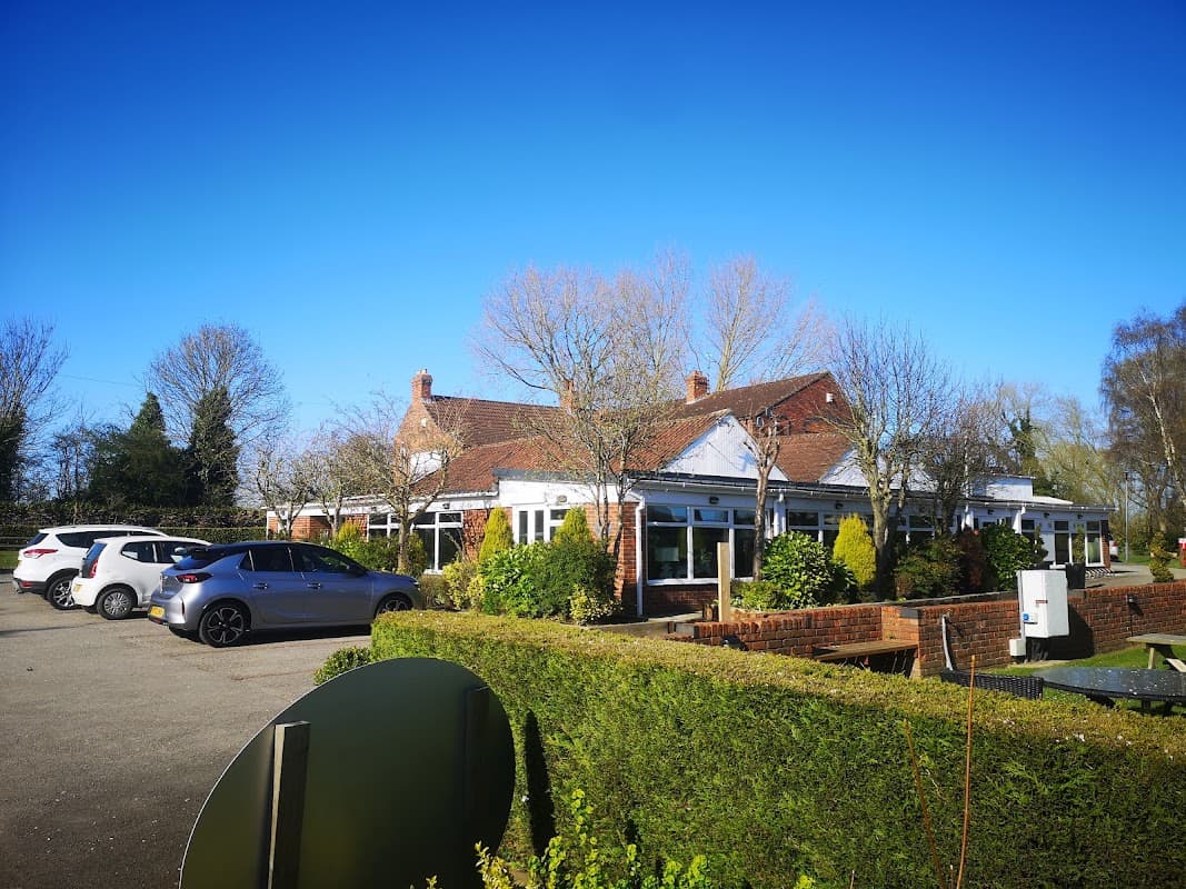 Cawood Park features a charming building surrounded by greenery and parked cars under a clear blue sky.