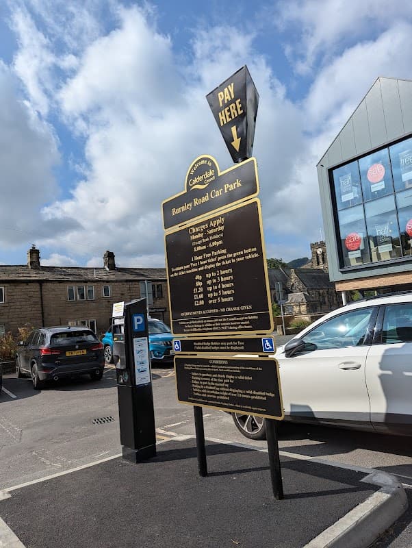 Burnley Road Car Park sign with parking fees, a payment arrow, and parked cars in Chiserley, Yorkshire.