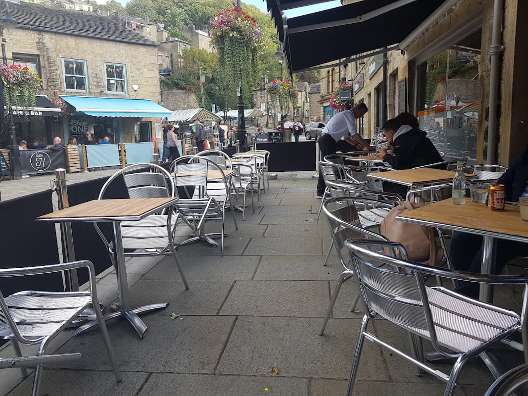 Outdoor seating area with metal chairs and tables, surrounded by shops and greenery in Chiserley, Yorkshire.