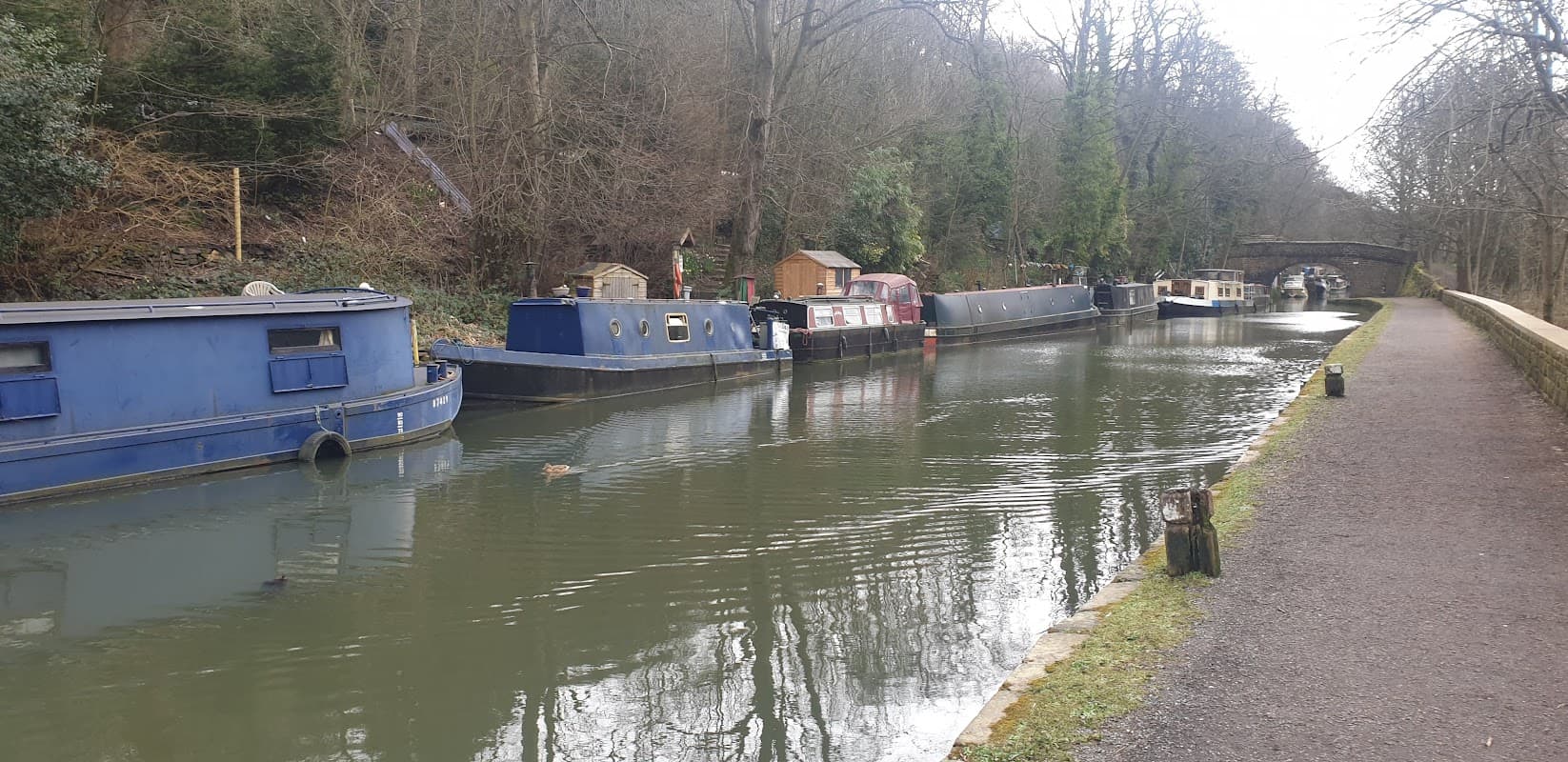Pay & Display car park near a canal lined with narrowboats and trees in Chiserley, Yorkshire.