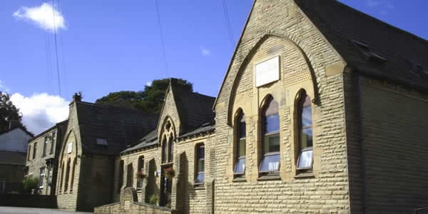 Historic stone building with arched windows, surrounded by greenery, located in Clayton, Yorkshire.