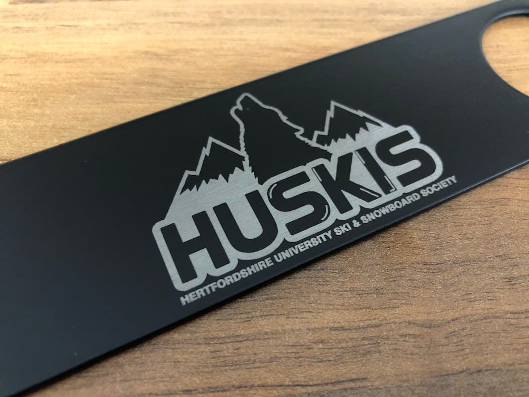 A black bar blade featuring the logo of Hertfordshire University Ski & Snowboard Society with mountains and a wolf.