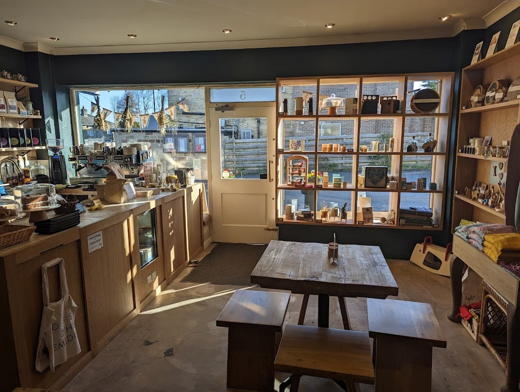 Bright shop interior featuring wooden shelves filled with products, a counter with coffee equipment, and a rustic table.