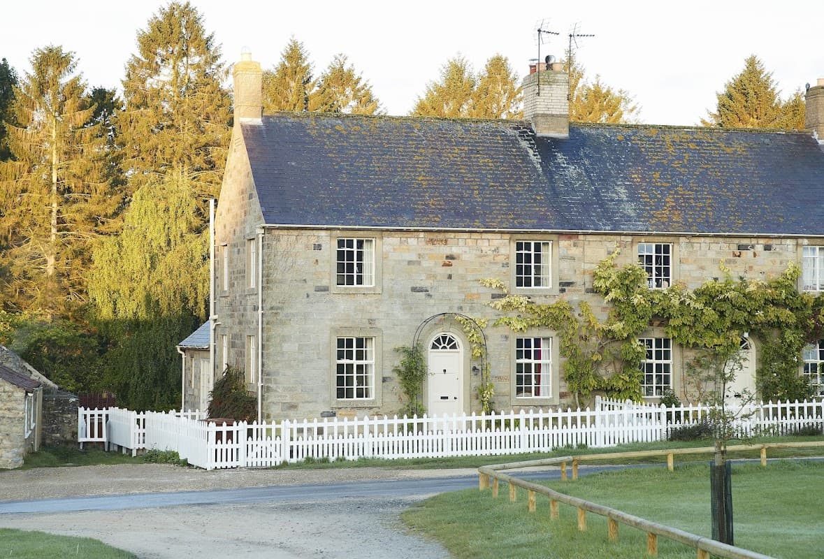 Charming stone cottage with a white picket fence, surrounded by trees in Coneysthorpe, Yorkshire.