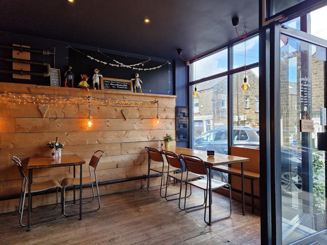 Cozy café with wooden walls, tables, chairs, and decorative string lights; large windows showcasing the street outside.