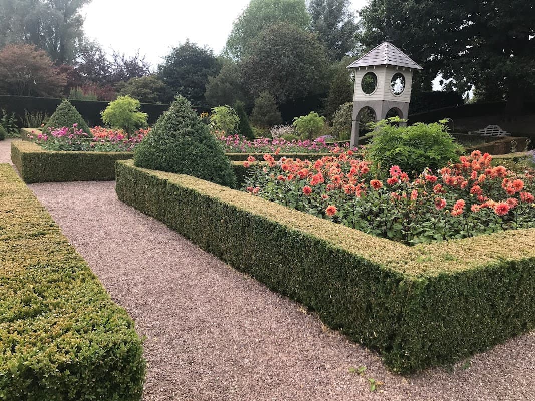 Lush garden featuring neatly trimmed hedges, colorful flower beds, and a decorative gazebo in Cullingworth, Yorkshire.