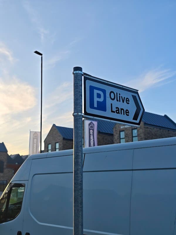 Sign for Olive Lane Car Park with a blue 'P' symbol, set against a clear sky and buildings in Darnall, Yorkshire.
