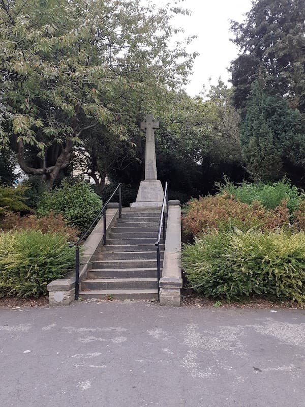 War memorial with a cross at the top of stone steps, surrounded by greenery in Denby Dale, Yorkshire.