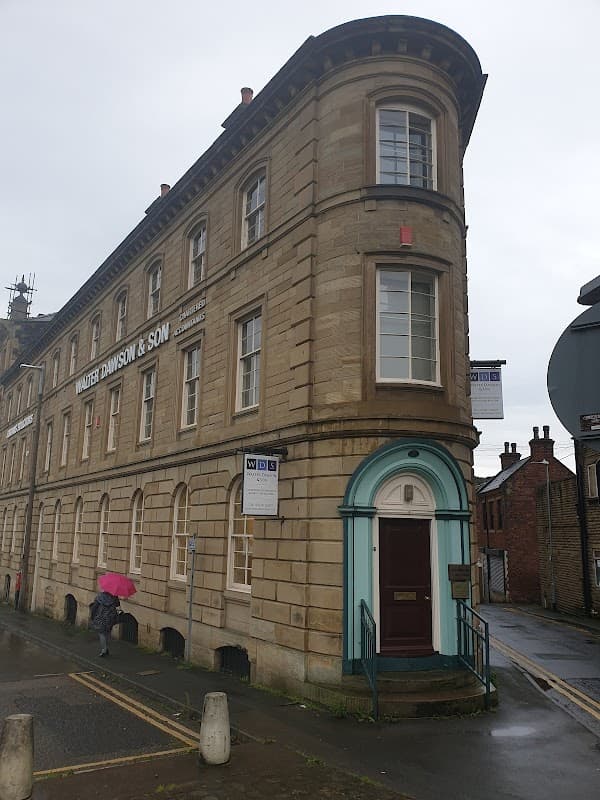 Walter Dawson & Son Car Park in Dewsbury, featuring a historic stone building with a curved corner and signage.
