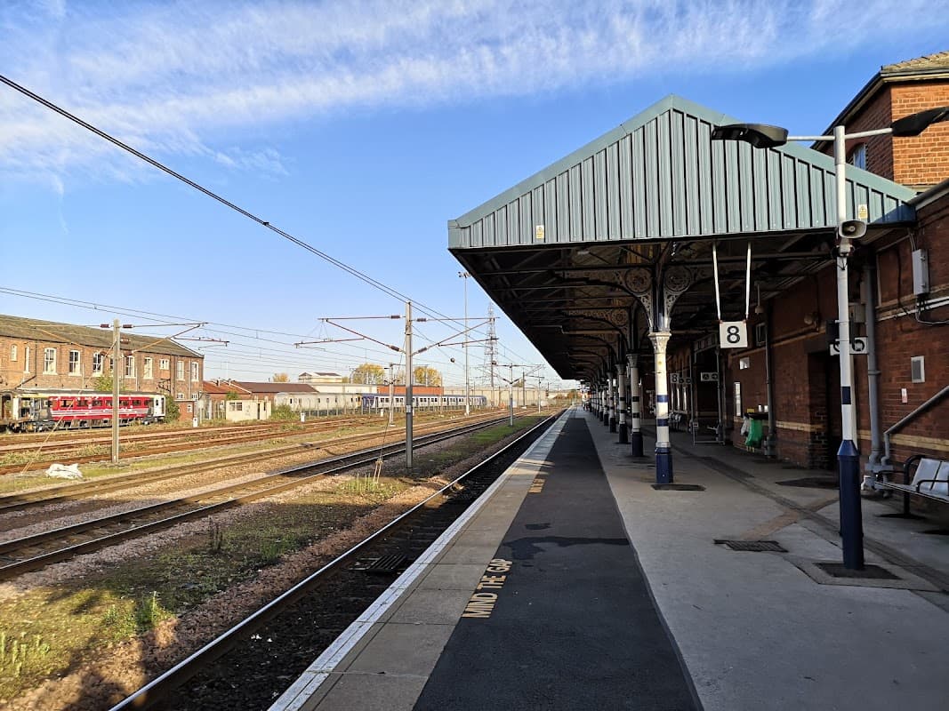Railway platform at Doncaster station, featuring tracks, trains, and a blue sky with scattered clouds.