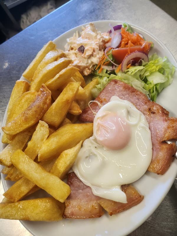 Plate of golden fries, a fried egg, ham, and a fresh salad with coleslaw and mixed vegetables.