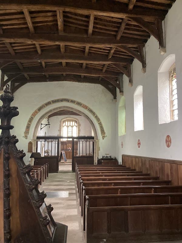 Interior of St Mary's Church featuring wooden beams, pews, and stained glass windows.