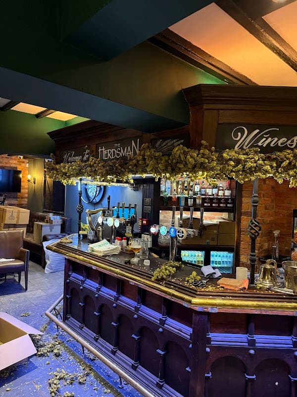 Welcoming bar area with wooden counter, beer taps, and decorative hops, set in a cozy pub atmosphere.