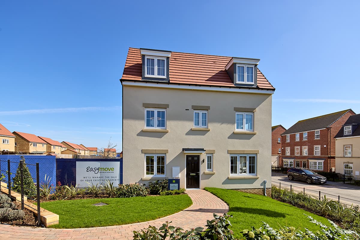 Modern three-story house with a red-tiled roof, surrounded by green grass and pathway, featuring a sign for Easymove.
