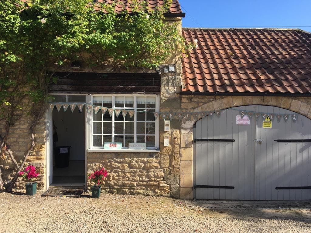 Charming stone building with a welcoming entrance, flower pots, and a rustic wooden door in Ebberston, Yorkshire.
