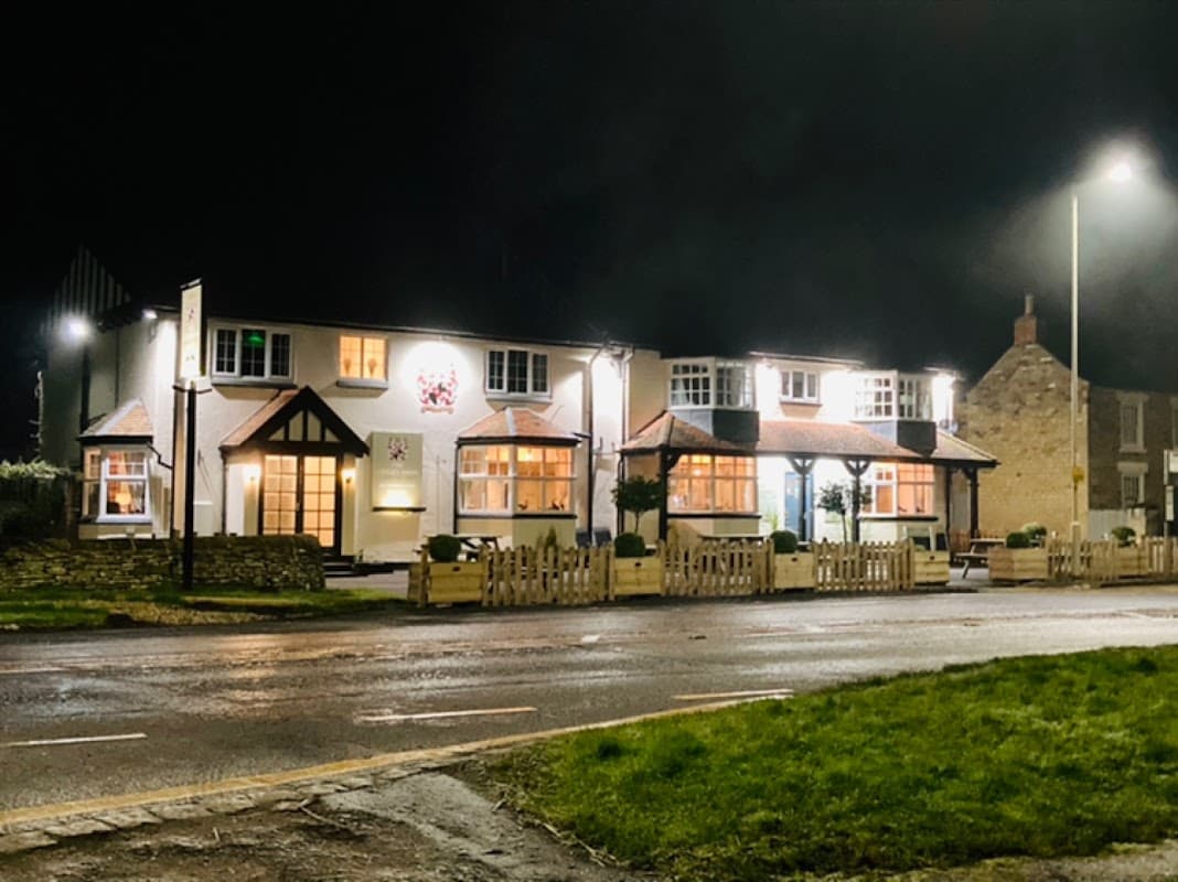The Cayley Arms pub illuminated at night, featuring a welcoming facade and surrounding greenery in Ebberston, Yorkshire.