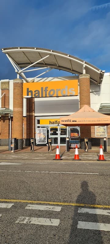 Halfords store entrance with large signage, orange awning, and traffic cones outside in Waterthorpe, Yorkshire.