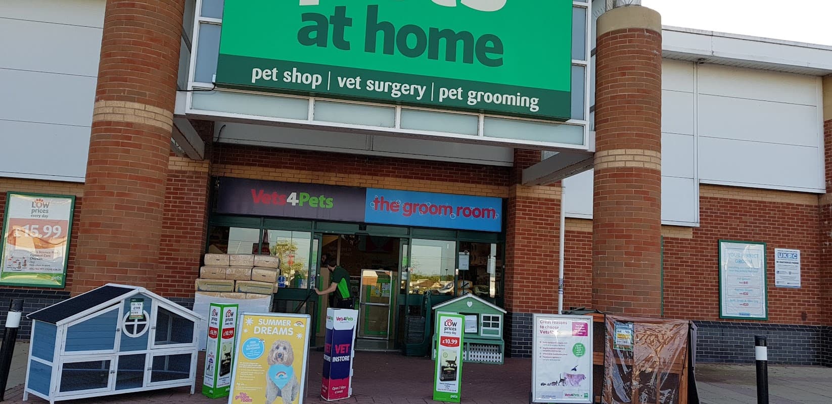 Bright storefront of Pets at Home, featuring signs for pet shop, vet surgery, and grooming services, with promotional displays.