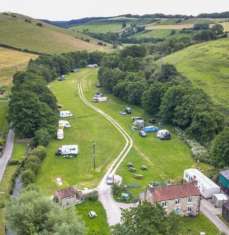 Aerial view of Low Farm Campsite in Ellerburn, featuring green fields, camping vehicles, and surrounding hills.