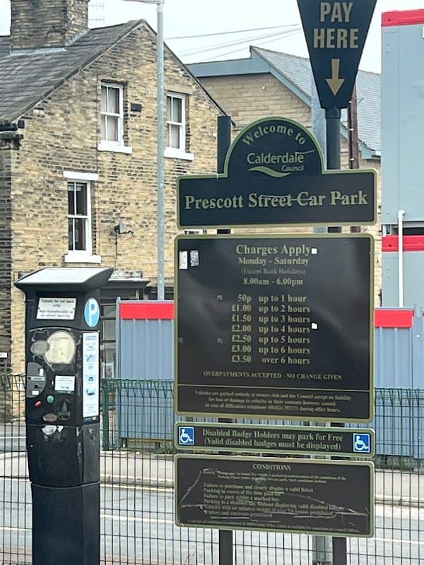 Sign for Prescott Street Car Park with parking charges and instructions, alongside a pay and display machine.